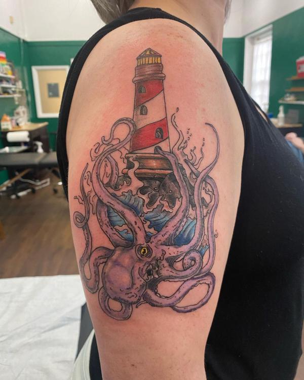 Lighthouse and kraken tattoo on upper arm