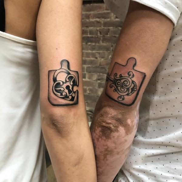 Lock and key puzzle couple tattoo on back of arm