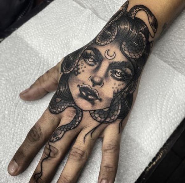 Medusa face with crescent moon and snake hand tattoo
