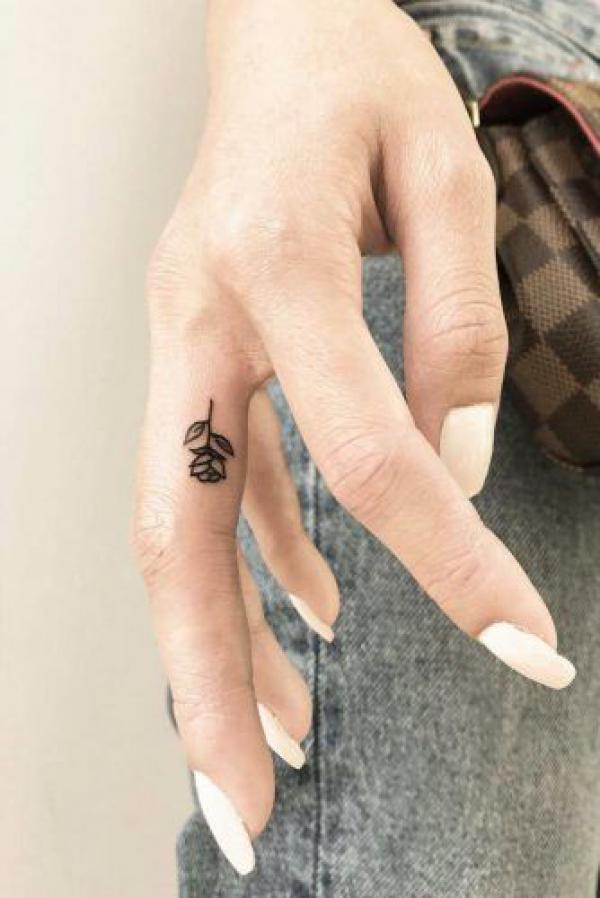 Minimalist rose tattoo on the side of middle finger