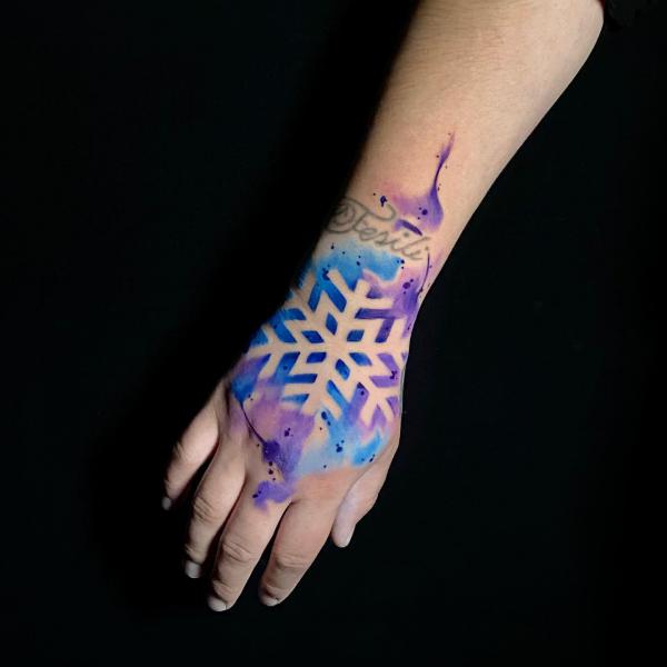 Negative space snowflake hand tattoo on watercolor backdrop
