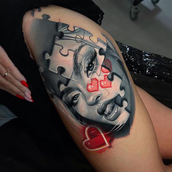 Puzzle face thigh tattoo