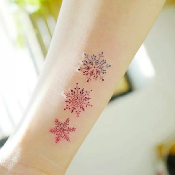 Red snowflake tattoo on forearm