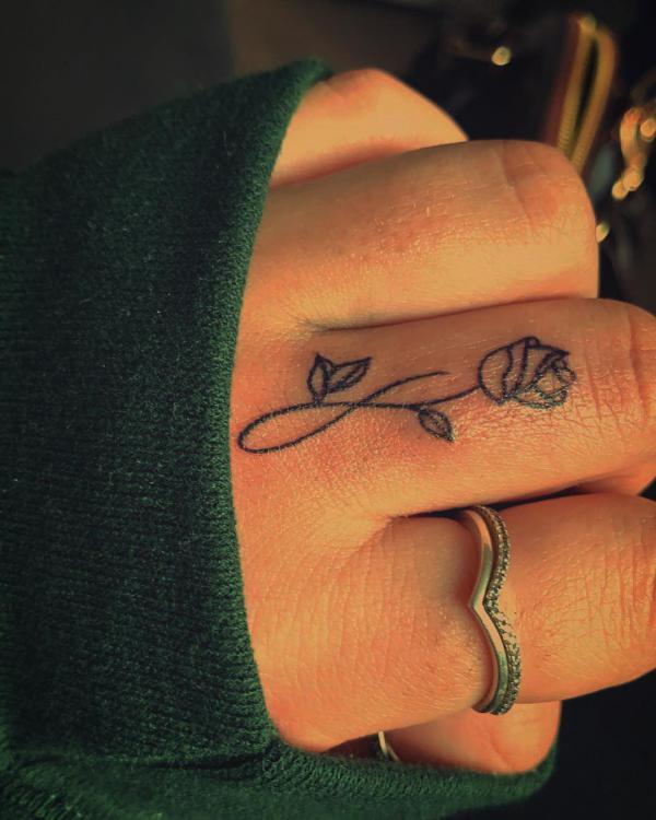Rose line work tattoo on middle finger