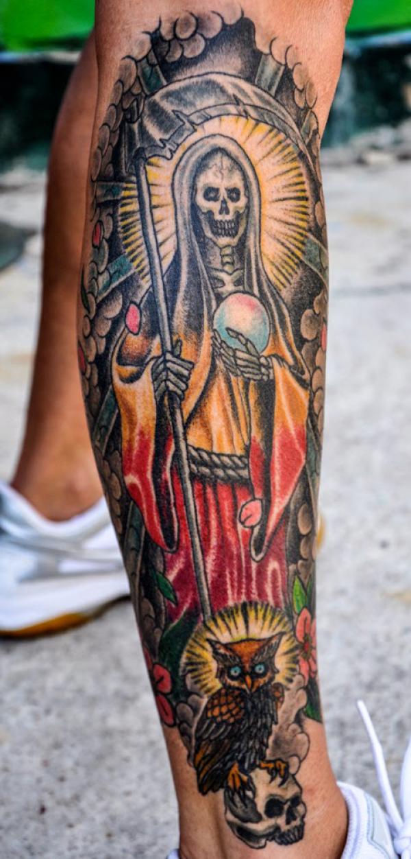 Santa Muerte holding scythe and globe with owl leg tattoo