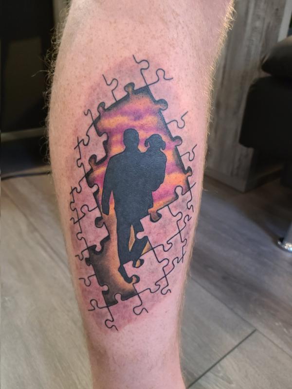 Silhouette father holding girl in puzzles tattoo