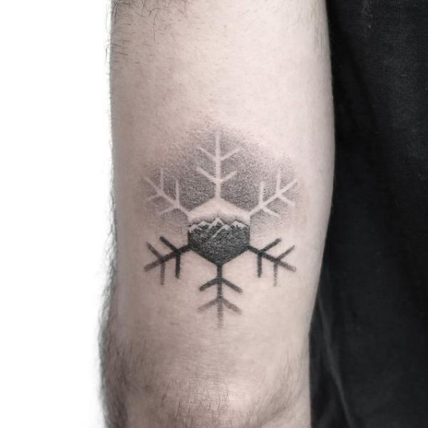 Snowflake dotwork tattoo above elbow