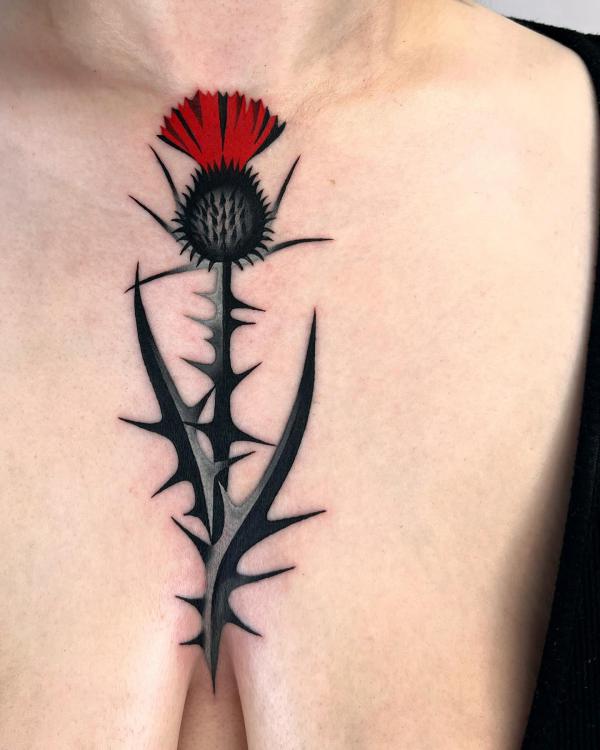 Stylized thistle above boob tattoo