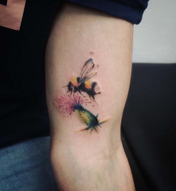 Thistle and bee tattoo above elbow