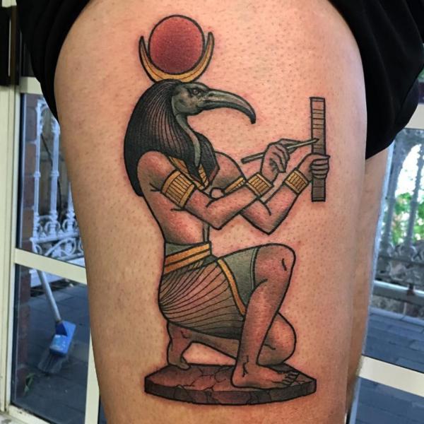 Thoth half kneeling and holding a stylus to write thigh tattoo