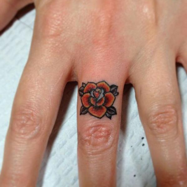 Traditional rose tattoo on middle finger