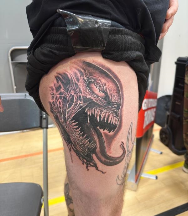 Venom face thigh tattoo