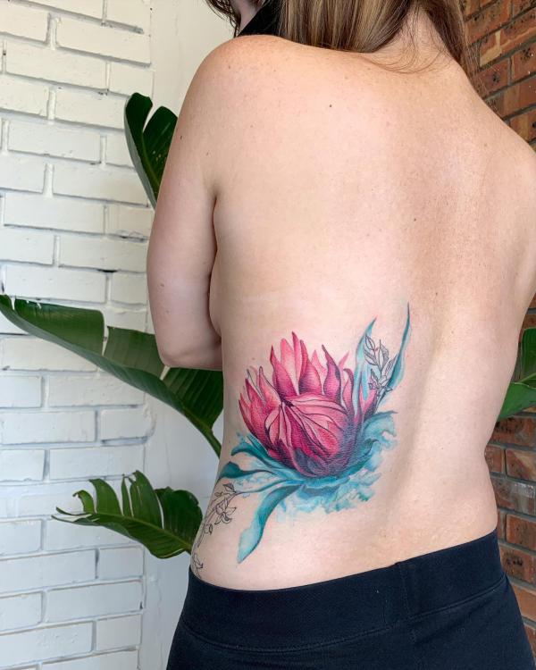 Watercolor protea tattoo on one side of low back