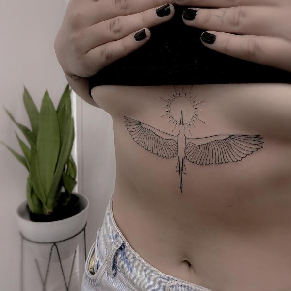 A bird flying high towards the sun sternum outline tattoo