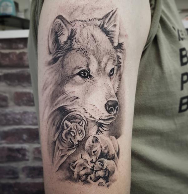 Black and gray wolf family tattoo on upper arm