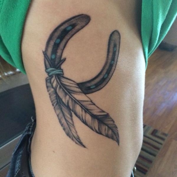 Black and grey horseshoe and feather side tattoo