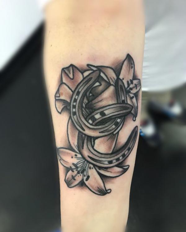 Black and grey horseshoe and lily tattoo