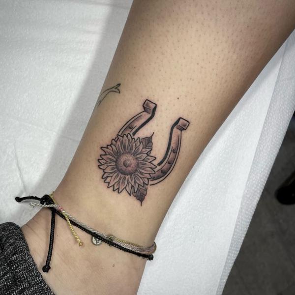 Black and grey horseshoe and sunflower tattoo