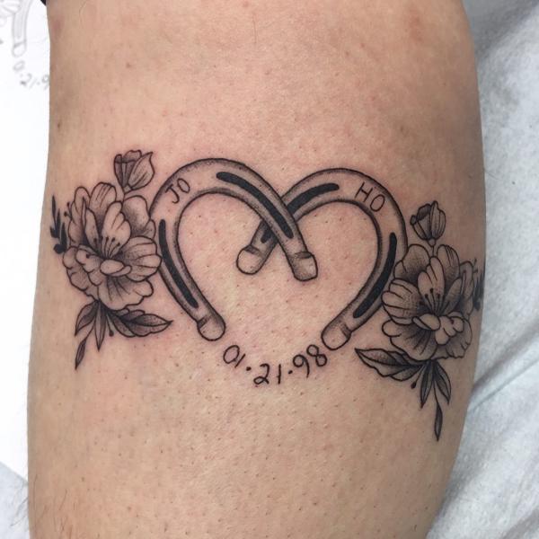Black and grey horseshoe heart with flower and date tattoo