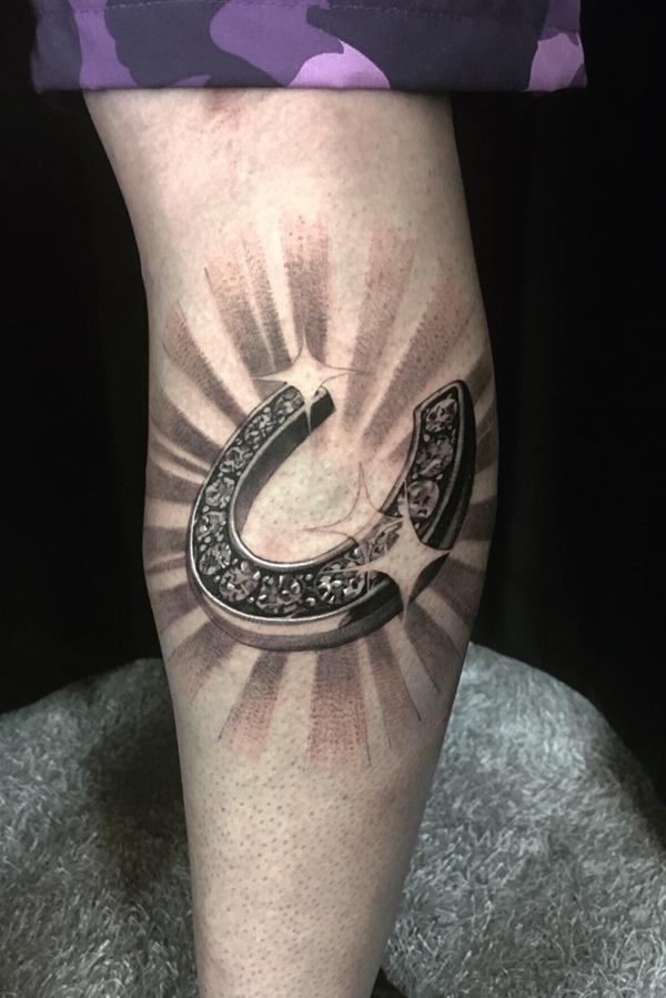 Black and grey horseshoe with halo tattoo