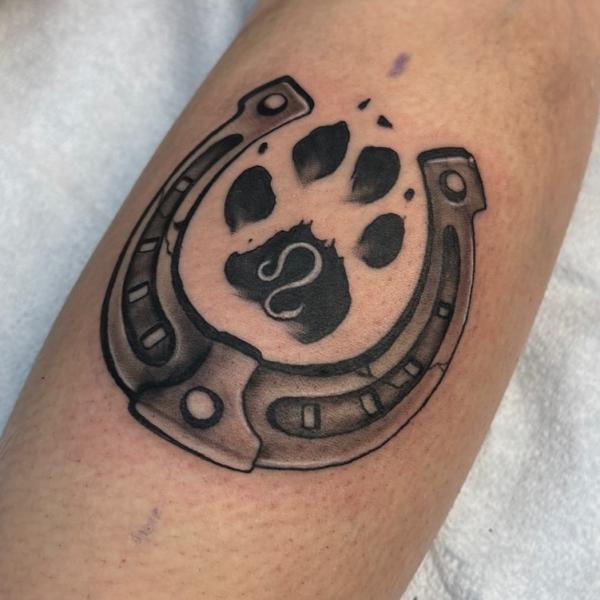 Black and grey horseshoe with paw print tattoo
