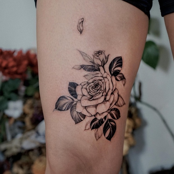 Black and grey rose tattoo above knee