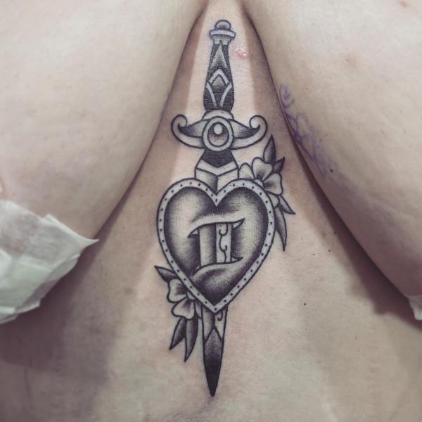 Black and white dagger through a heart sternum tattoo traditional