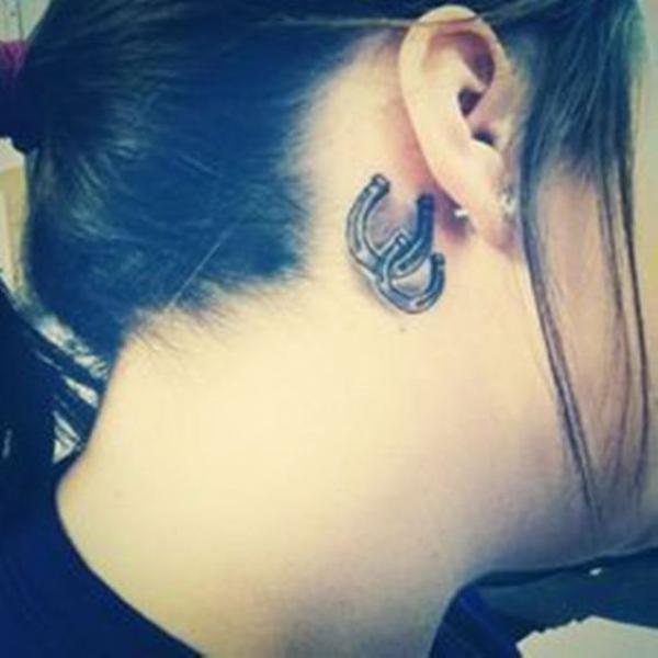 Black and white horseshoe tattoo behind ear