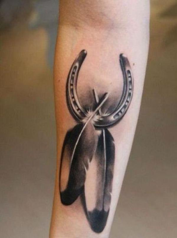 Black and white horseshoe with a pair of feathers tattoo