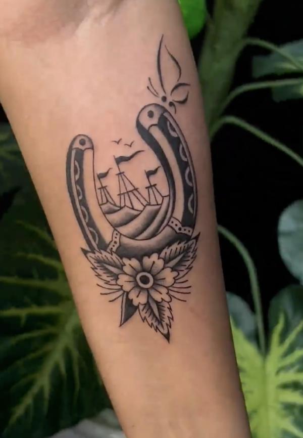 Black and white traditional horseshoe and sailing boat tattoo