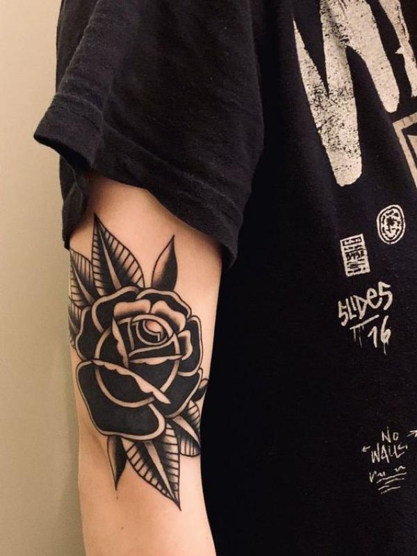 Black and white traditional rose tattoo on the side of elbow