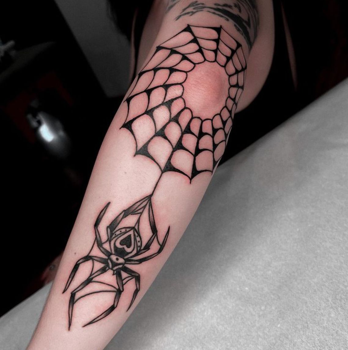 Black and white traditional spider web with a falling spider elbow tattoo