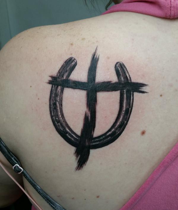Black horseshoe with cross stroke shoulder blade tattoo