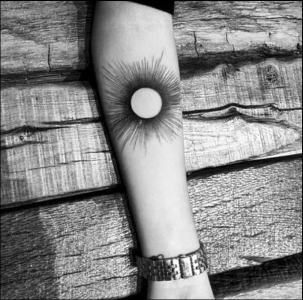 Black ink sun tattoo below inner elbow