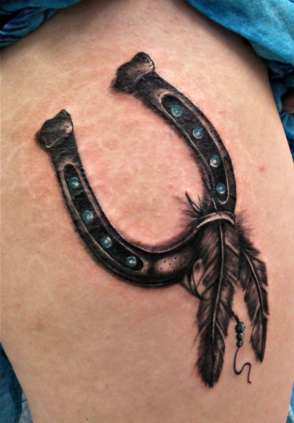 Blackwork horseshoe and feather tattoo
