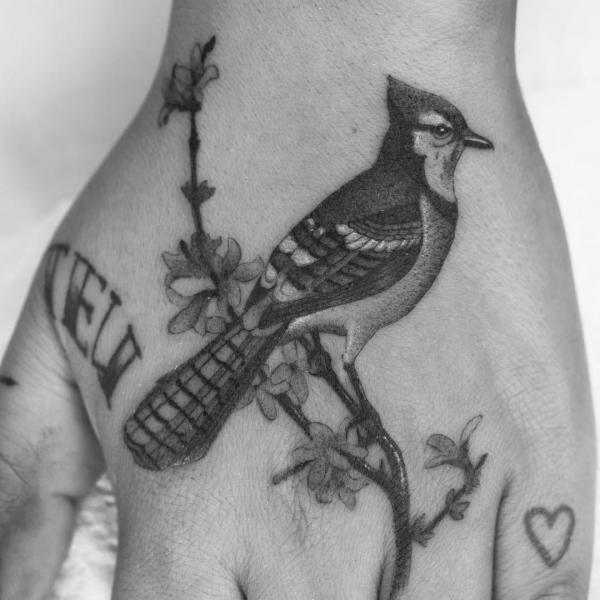 Blue Jay perched on branch hand tattoo black and grey