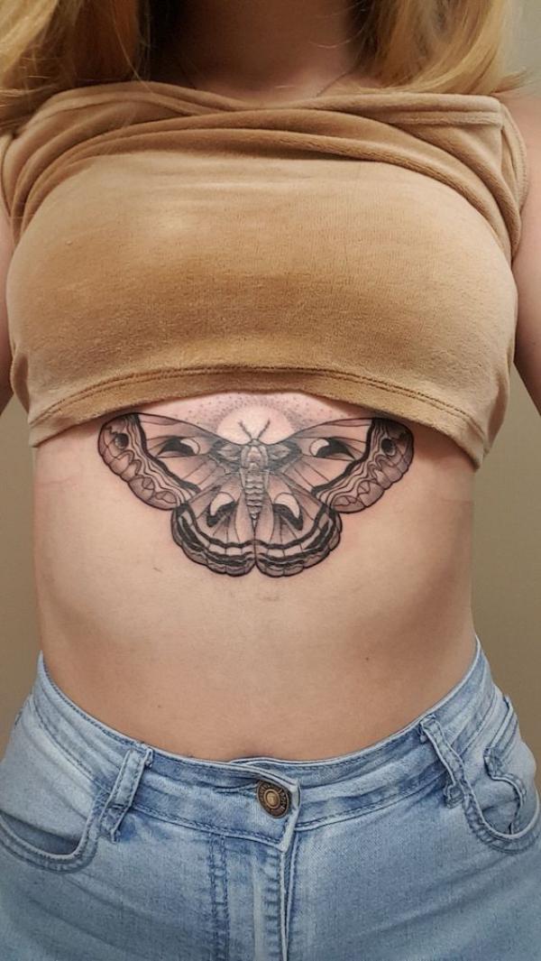 Butterfly with sun underboob tattoo