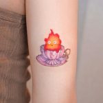 Calcifer in cup back of arm tattoo