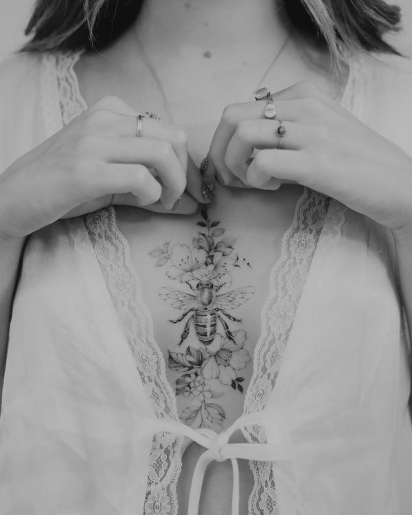 Dainty bee with flowers sternum tattoo