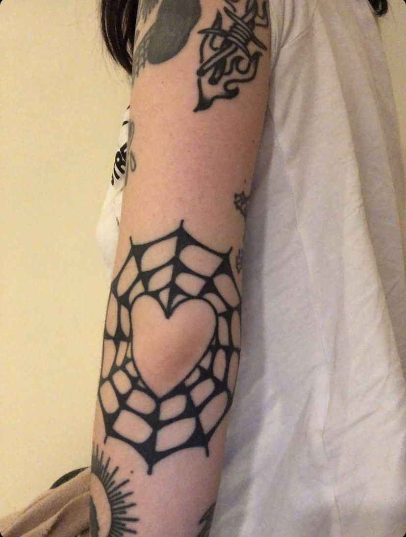Elbow spiderweb with central heart tattoo black and white