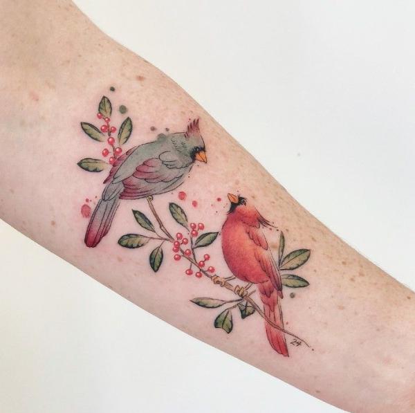 Feminine cardinal pair on holly branch tattoo