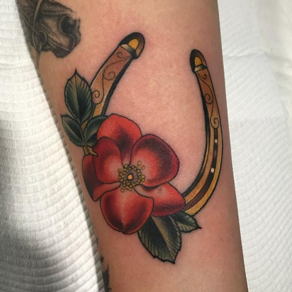 Golden horseshoe and red flower tattoo