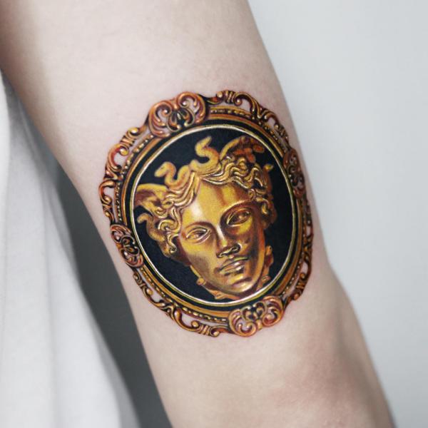 Golden metallic Medusa frame tattoo