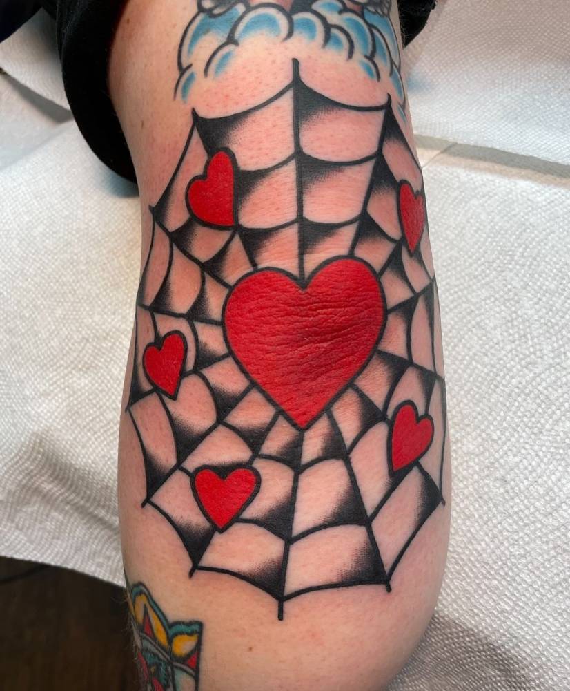 Heart and spiderweb tattoo on elbow
