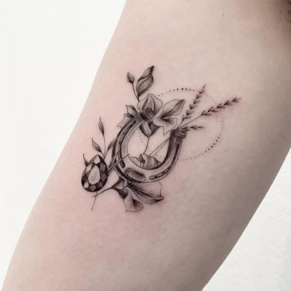 Horseshoe and diamond with calla lily tattoo black and grey