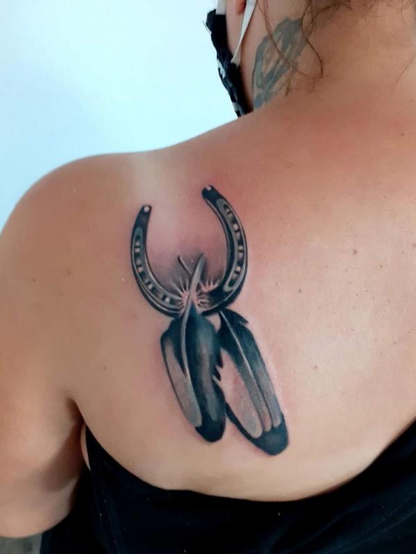 Horseshoe and feather shoulder blade tattoo