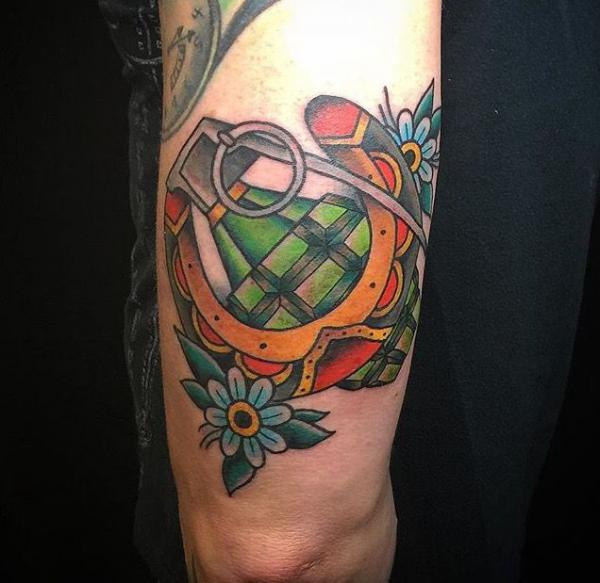 Horseshoe and hand grenade back of arm tattoo