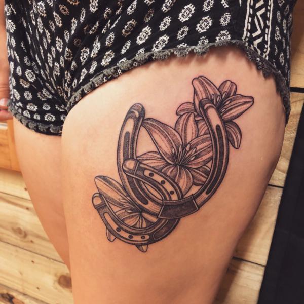 Horseshoe and lily thigh tattoo