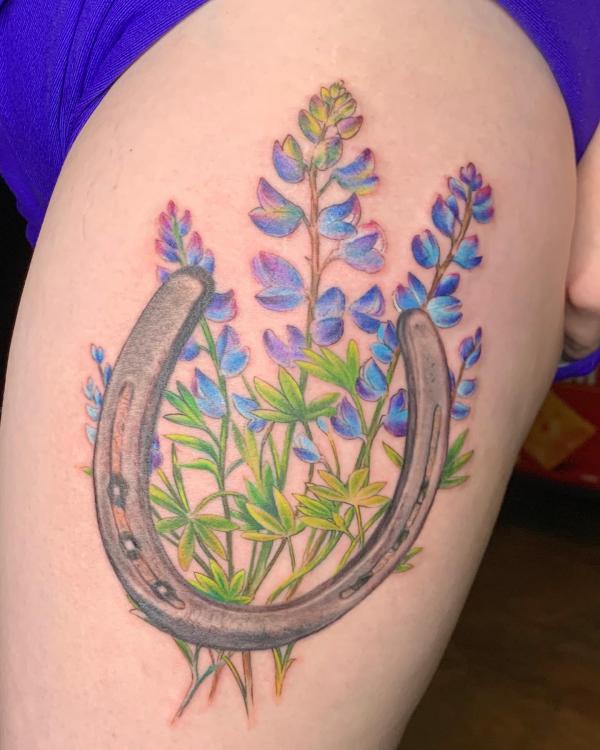 Horseshoe and lupine thigh tattoo