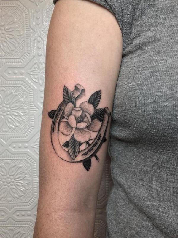 Horseshoe and magnolia tattoo black and grey
